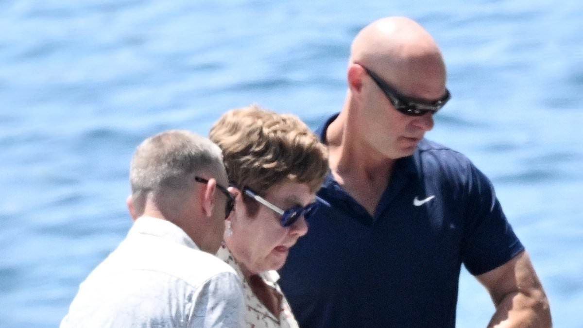 Sir Elton John is assisted off a boat in Italy with David Furnish